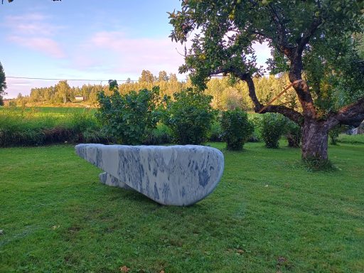 Künstler Jan Moritz Stahl - Großer grauer Stein auf einer Wiese, umgeben von Bäumen und Sträuchern.