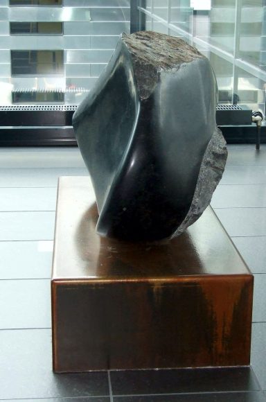 Künstler Jan Moritz Stahl - Abstrakte Skulptur aus dunkelgrauem Material auf braunem Sockel.