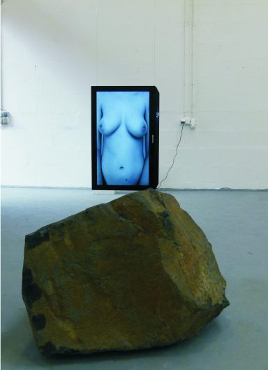 Künstler Jan Moritz Stahl - Ein Fernseher zeigt einen nackten Oberkörper, daneben liegt ein großer Stein.