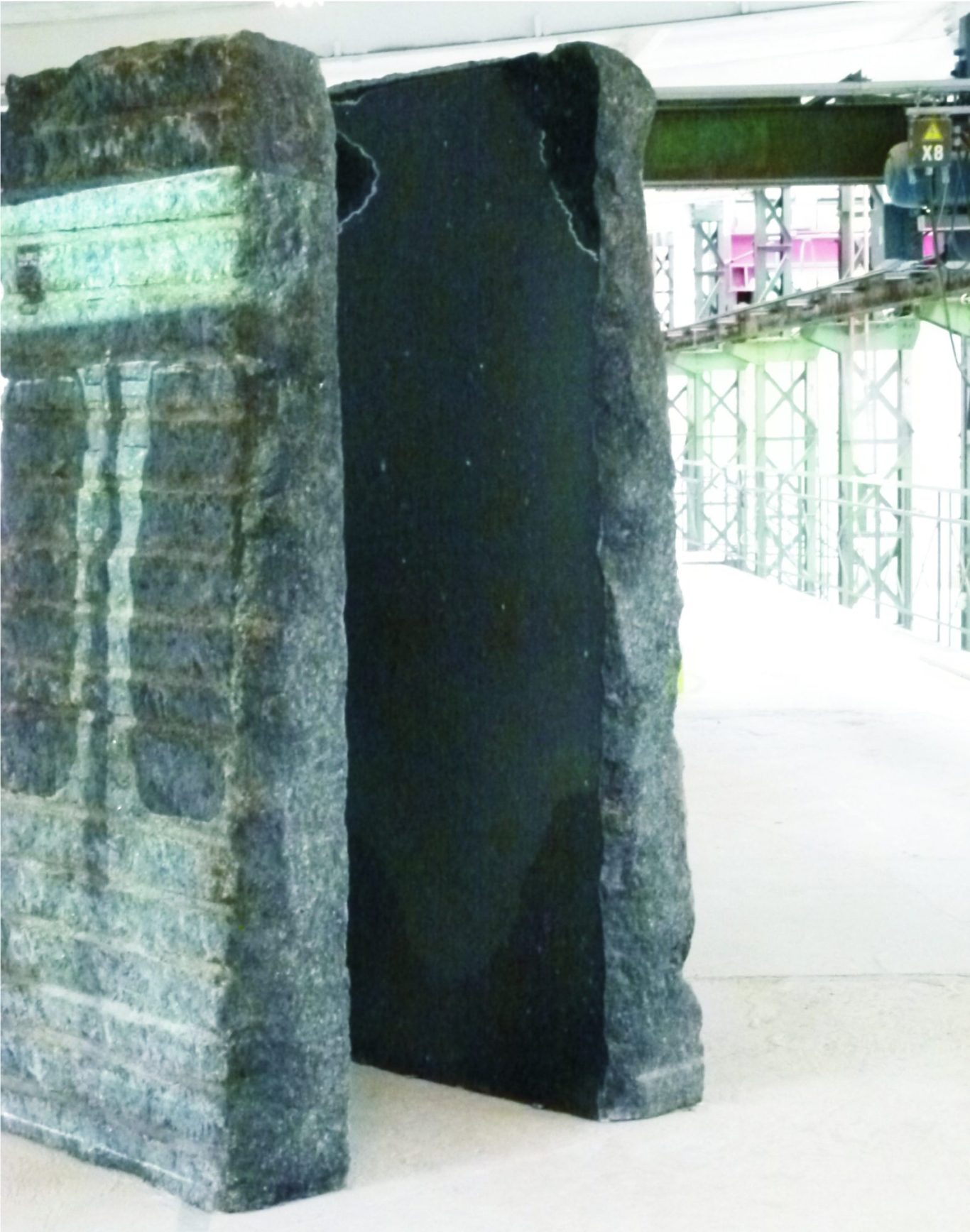 Im Zuge Künstler Jan Moritz Stahl - Dunkler Steinsockel mit zwei großen, vertikalen Platten in einer modernen Umgebung.