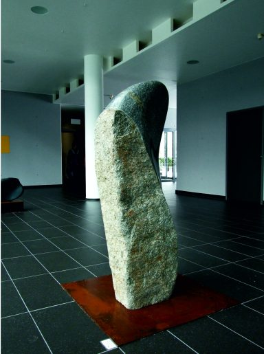 Vom Künstler Jan Moritz Stahl - Steinerne Skulptur in modernem Raum mit glatten Wänden und Fliesenboden.