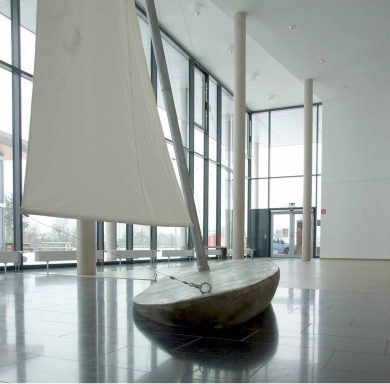 Künstler Jan Moritz Stahl - Ein Modellboot mit Segel steht in einem modernen, lichtdurchfluteten Raum.