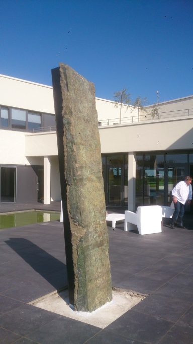 Künstler Jan Moritz Stahl - Ein schmaler, aufrechter Stein auf einem Platz vor einem modernen Gebäude.