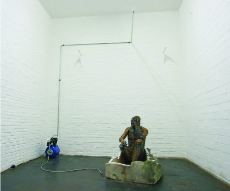 Künstler Jan Moritz Stahl - Eine Person sitzt in einer Betonvertiefung in einem leeren, weißen Raum.