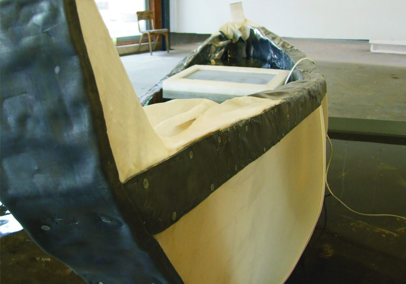 Der Boot Blick auf einen Bootsrumpf in einem Innenraum, mit einem weißen Bezug und schwarzem Rand.