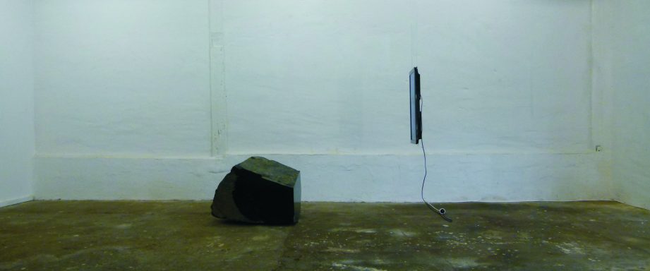 Künstler Jan Moritz Stahl - Ein leerer Raum mit einem schwarzen Würfel und einem vertikalen schwarzen Objekt an der Wand.