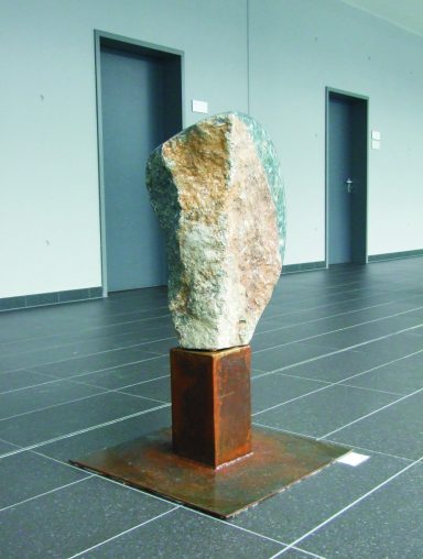 Künstler Jan Moritz Stahl- Skulptur aus Stein auf metallischem Sockel in einem modernen Raum.