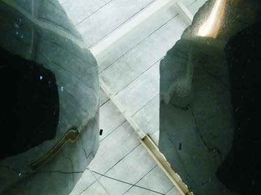 Künstler Jan Moritz Stahl - Zwei dunkle Objekte mit reflektierender Oberfläche über einem hellen Holzboden.