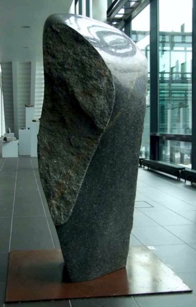 Vom Künstler Jan Moritz Stahl - Steinerne Skulptur in modernem Raum mit glatten Wänden und Fliesenboden.